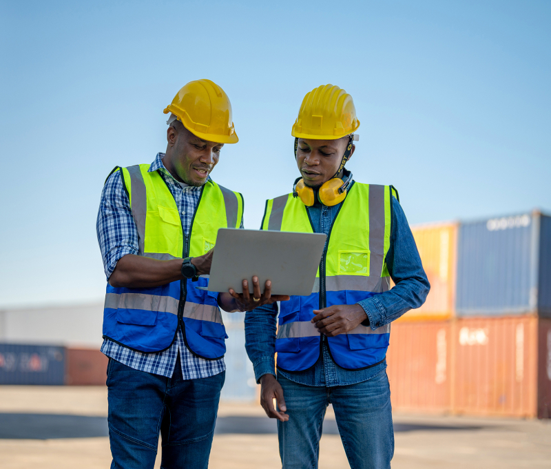 African workers, Engineer, Technician holding laptop for checking and inspecting on site containers area for shipping transportation. Concept people operation in heavy industrial.